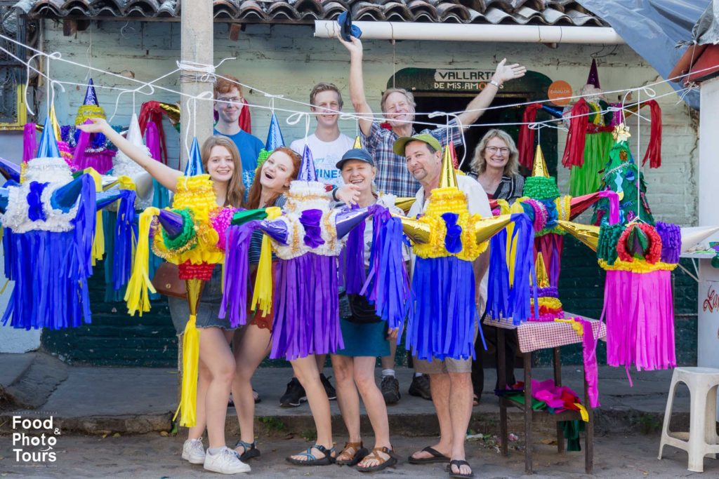 Two American families posing at a piñata shop while taking a Food Tour by Puerto Vallarta Food Tours and Photo Tours, created by Star aka Estrellita Velasco