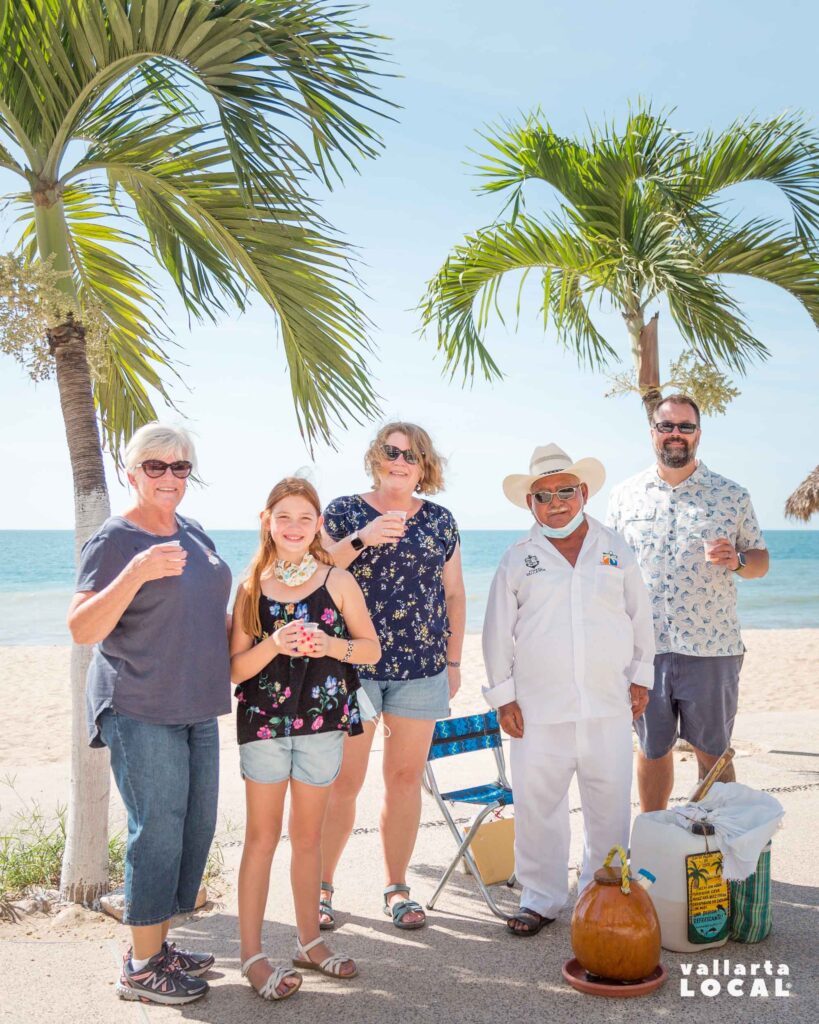 American family on vacation in Puerto Vallarta's Malecon posing next to a local selling a coconut drink called Tuba.