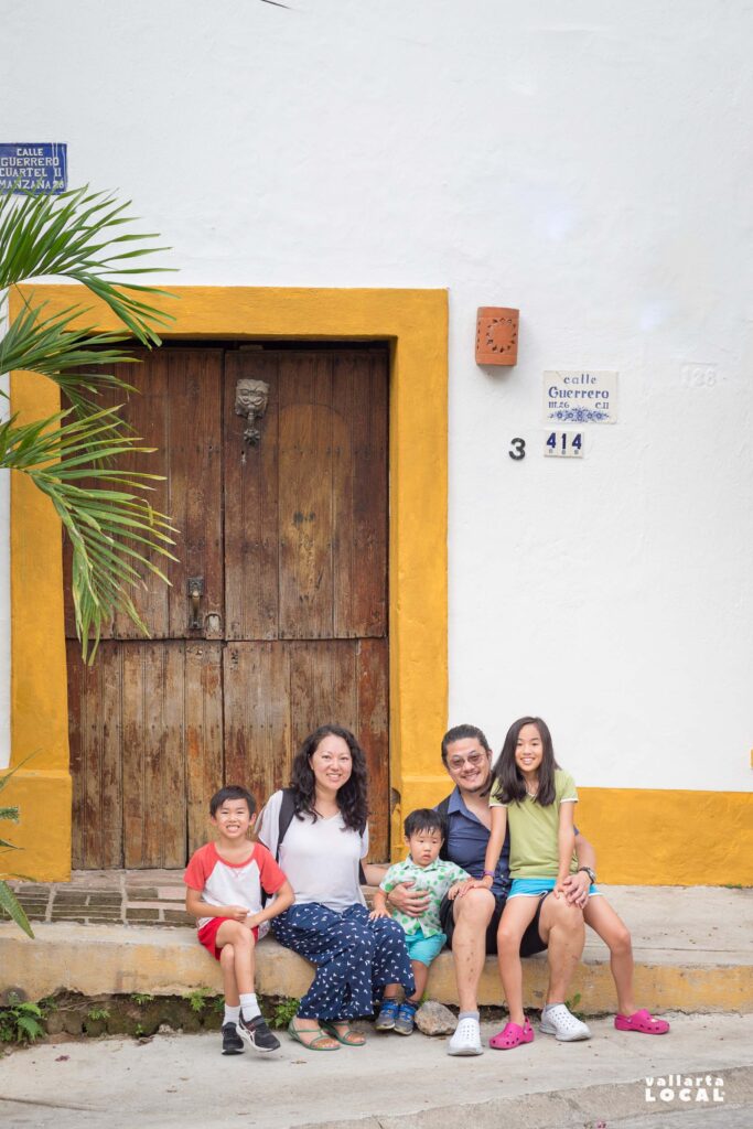 Asian-American family on vacation in Puerto Vallarta posing outside of an old home in Gringo Gulch while taking a City Tour with a Mexican owned food tour operator in Puerto Vallarta